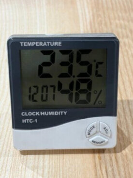 Digital humidity and temperature meter reading 23.5°C and 48% RH on a hardwood floor, demonstrating ideal indoor conditions for fitting wood flooring.